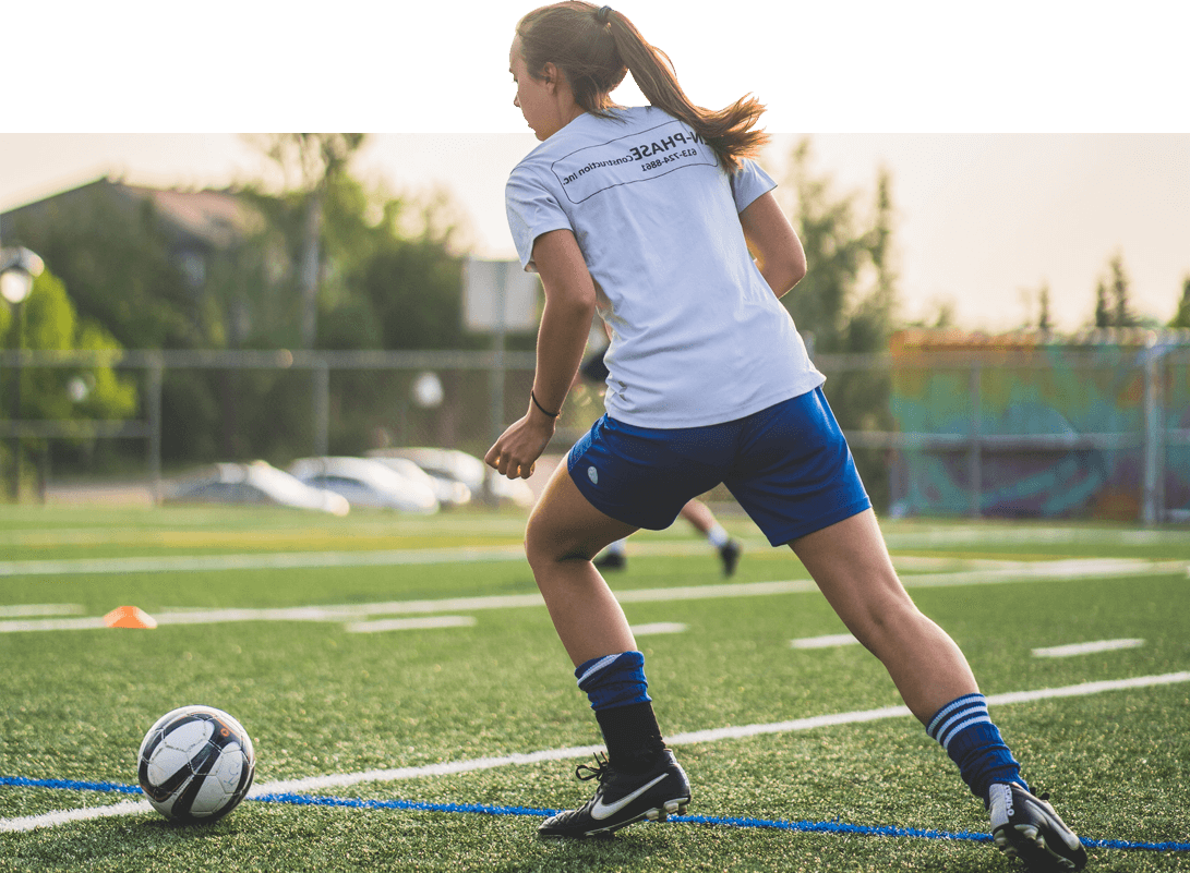 Teenage Female Footballer Practicing Kick to Goal